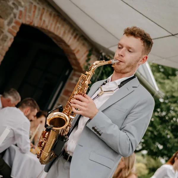 OSKARSAX v obleku hraje na saxofon během svatebního dne